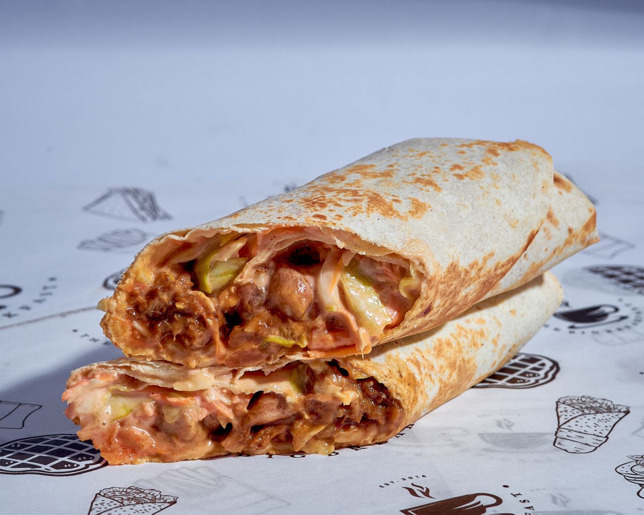 Appetizing burrito with meat and veggies, wrapped in tortilla and sliced open for a mouth-watering view.